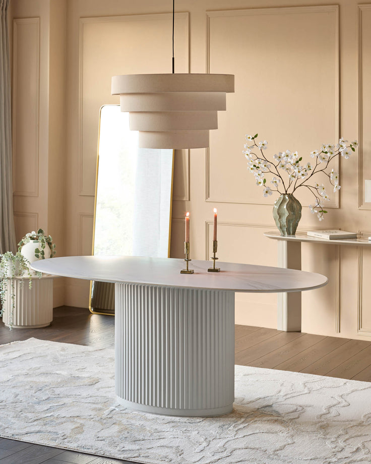 Austin ceramic fluted dining table in white with oval top and ribbed cylindrical base in a modern dining room setting.