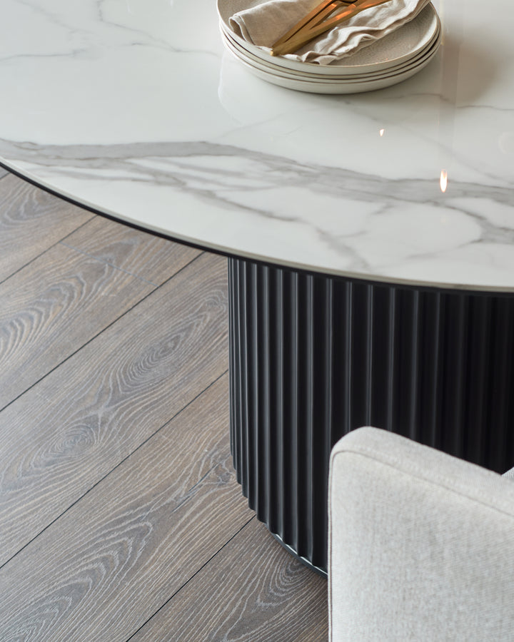 Austin 6-seater dining table with white marble ceramic top and black fluted base, angled view showing table design and styling.