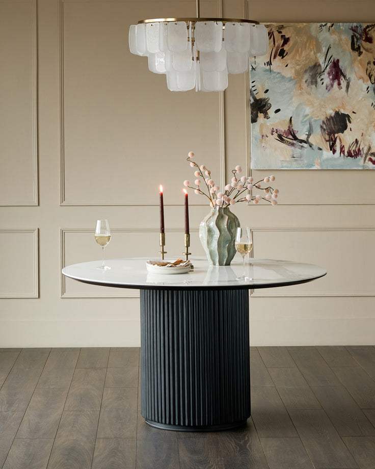 Austin 6-seater dining table with white ceramic top and black ribbed cylindrical base, styled in modern dining room setting.