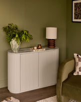 Austin Compact Sideboard in natural ceramic with vertical ribbed detailing, marble top, displayed in a styled living room setting.