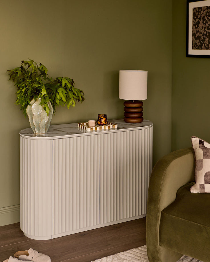 Austin Compact Sideboard in natural ceramic with vertical ribbed detailing, marble top, displayed in a styled living room setting.