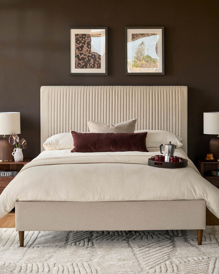 Cream fabric king-size bed with vertical ribbed headboard and wooden legs, displayed in a styled bedroom setting.
