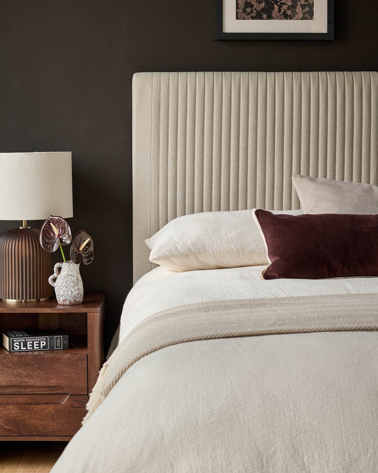 Cream fabric king-size bed with vertical channel tufting headboard, shown in a styled bedroom setting with pillows and bedding.