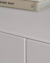 Close up of a light grey chest of drawers with a book resting on the top.