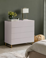 Contemporary chest of drawers with lamp, flowers and books on top. A bedroom setting creates an inviting scene.