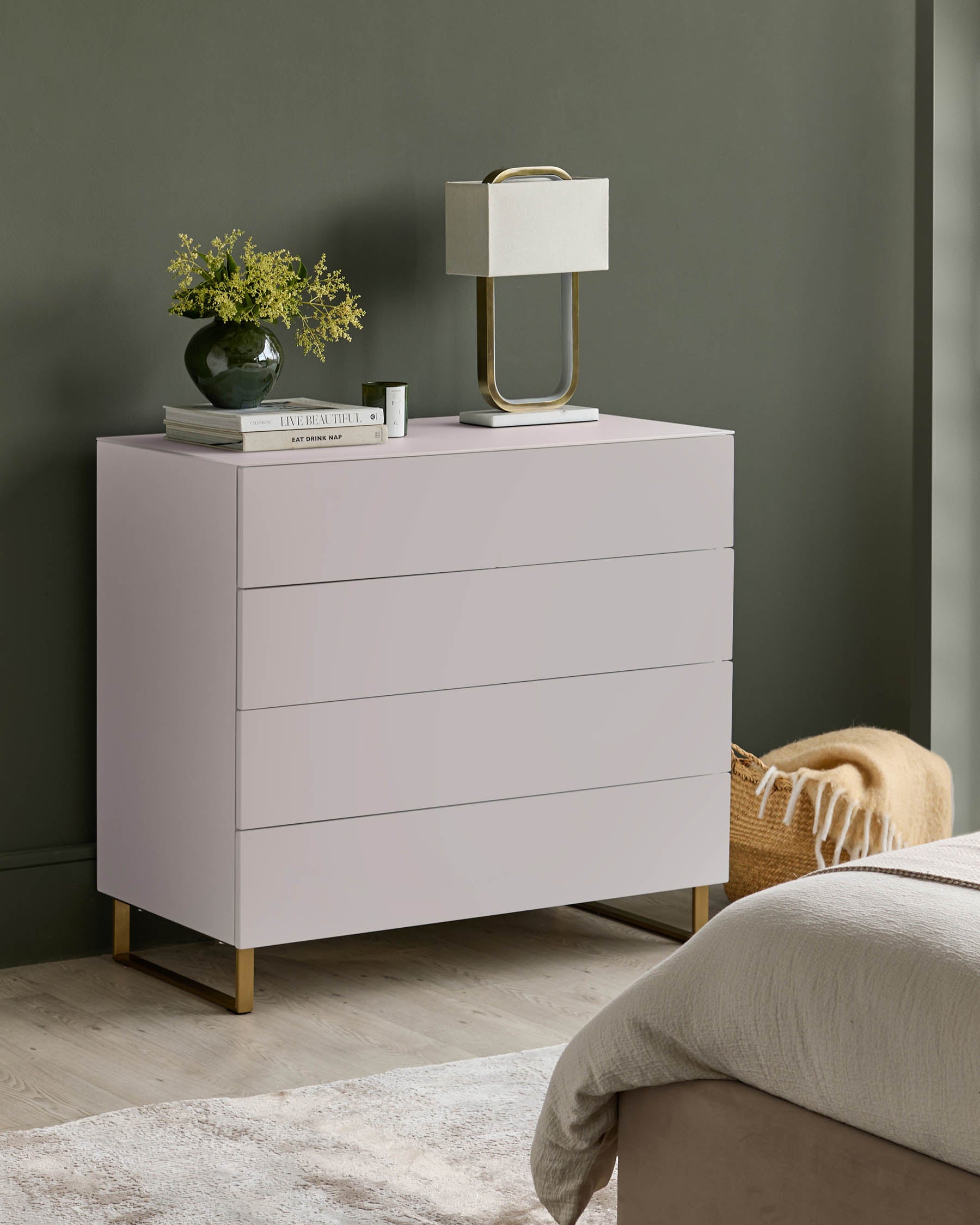 Contemporary chest of drawers with lamp, flowers and books on top. A bedroom setting creates an inviting scene.