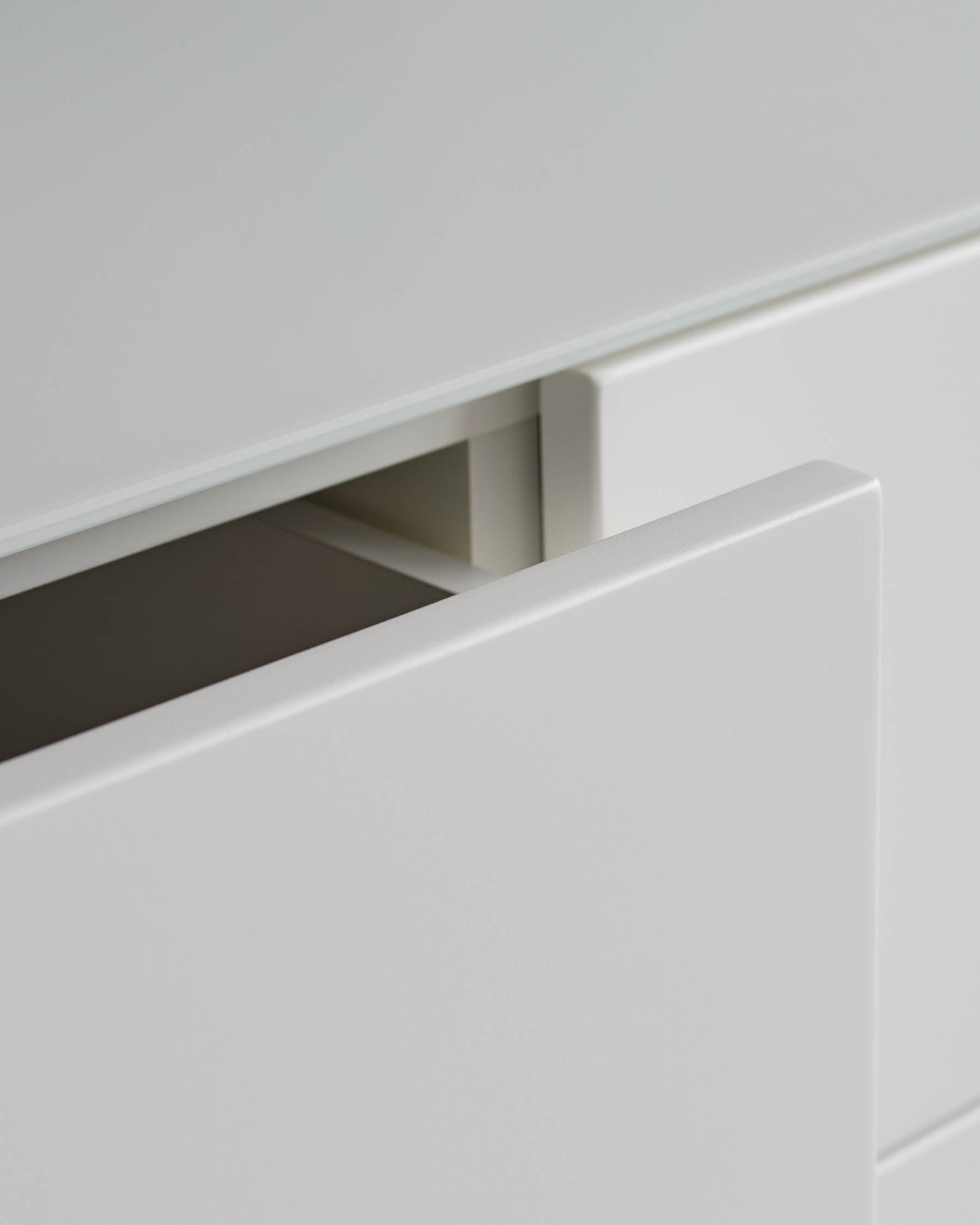 A minimalist white drawer unit with one drawer slightly open. Clean lines for a modern look.