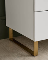 Close-up of a sleek, modern vanity unit with white drawers and gold metal legs, showcasing its stylish design.