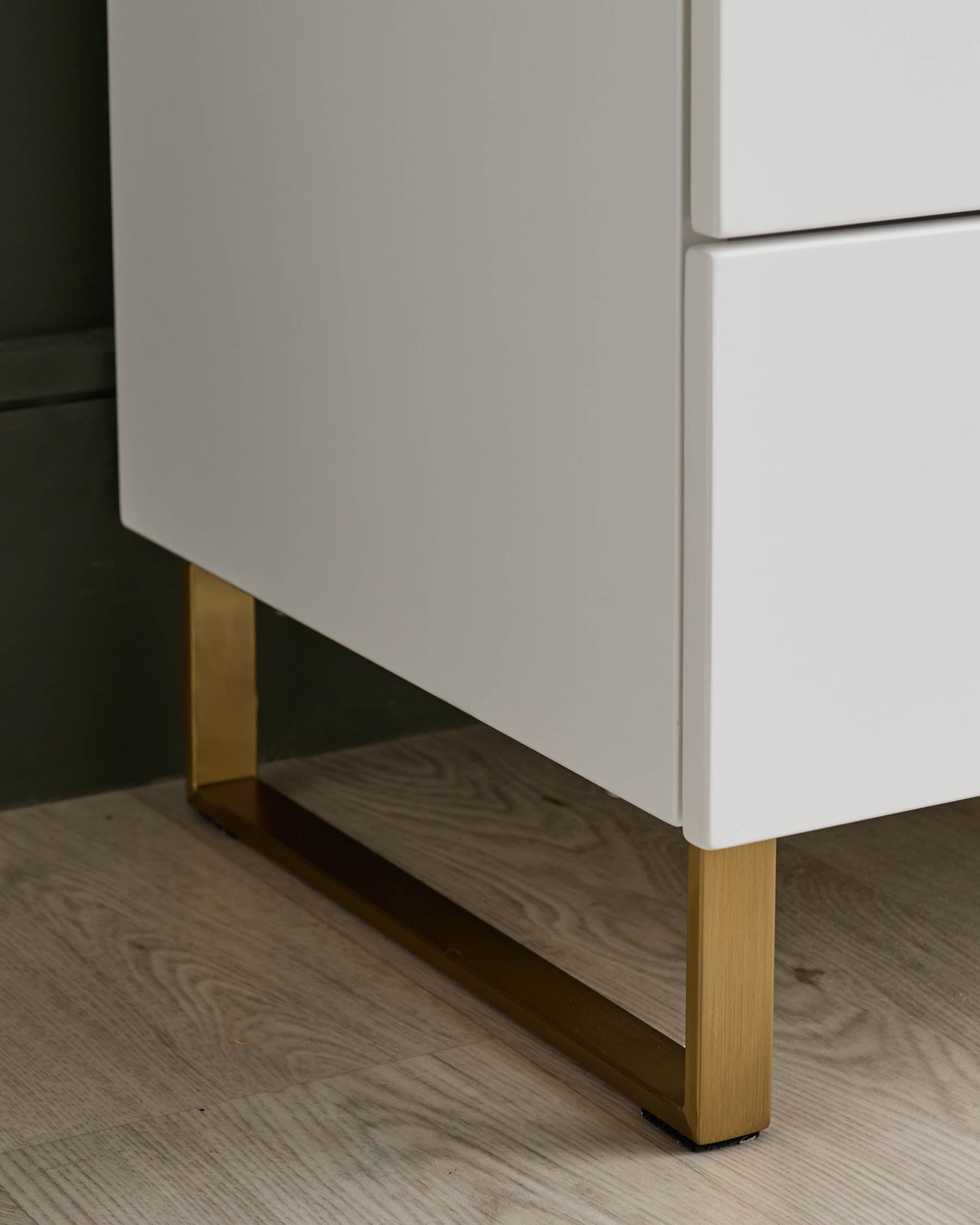 Close-up of a sleek, modern vanity unit with white drawers and gold metal legs, showcasing its stylish design.