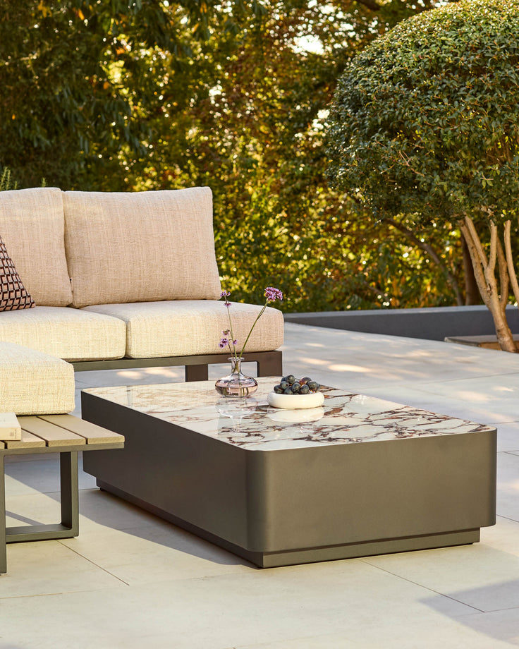 Bianco garden coffee table with black base and white Calacatta marble top, displayed on a patio with cream cushioned seating.