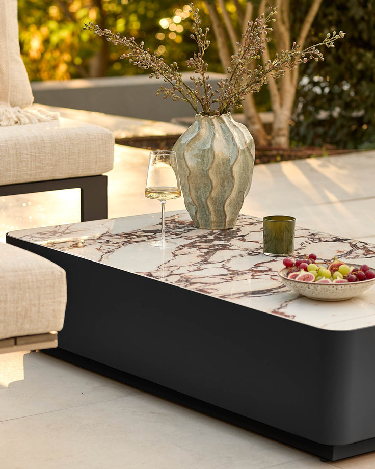 Bianco garden coffee table with black base and white Calacatta marble top, styled on outdoor patio with décor.