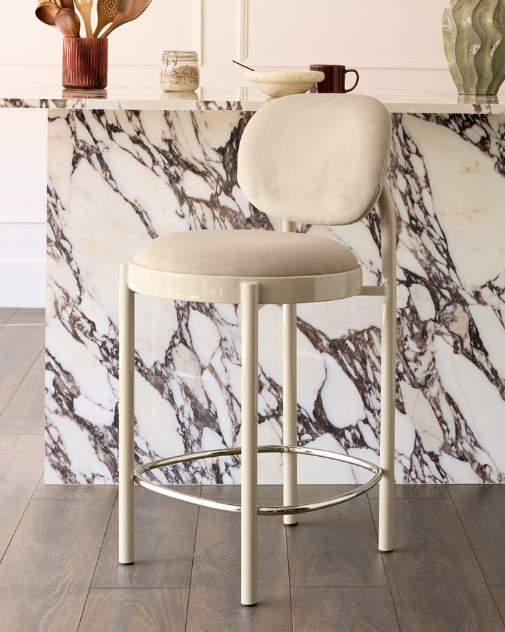 Blake bar stool in champagne velvet with cream metal frame and footrest, shown in modern kitchen setting.