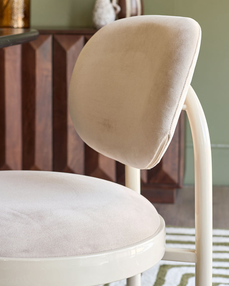 Blake dining chair in champagne velvet, shown from side angle displaying curved backrest and round seat.