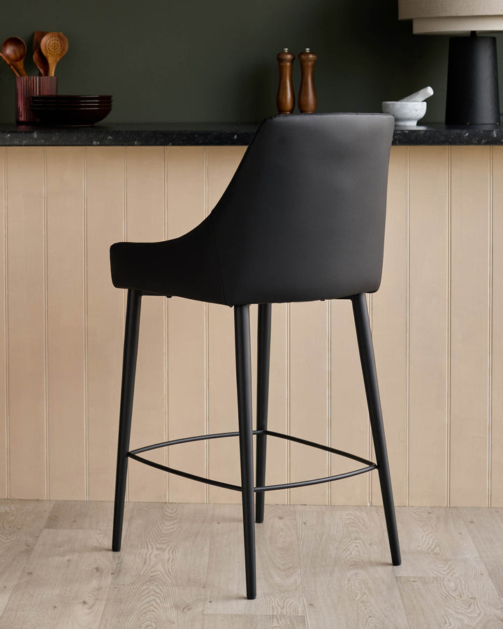Blakely black faux leather bar stool with curved backrest, black legs, and footrest, shown from rear angle.
