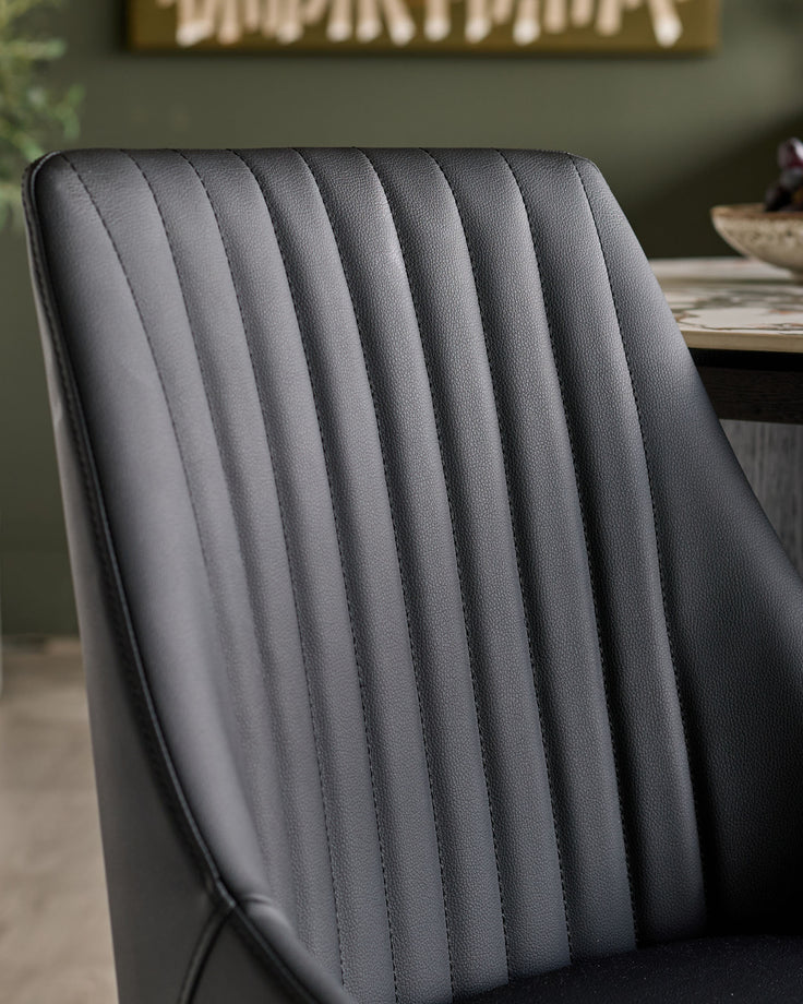 Blakely faux leather dining chair in black with vertical channel quilting detail, close-up of backrest.