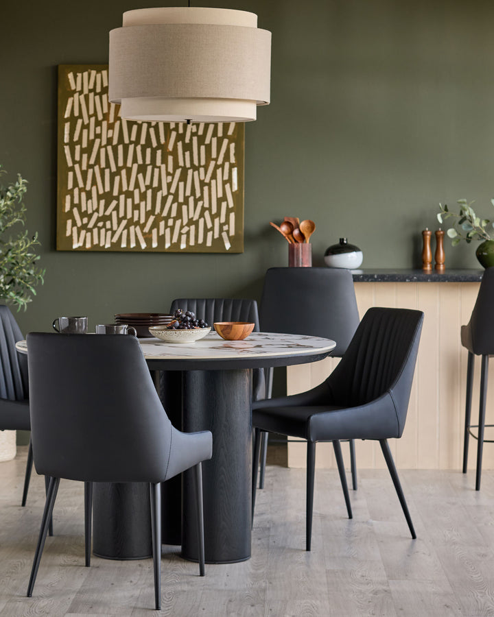 Blakely black faux-leather dining chair with quilted backrest and metal legs in a modern dining room setting.