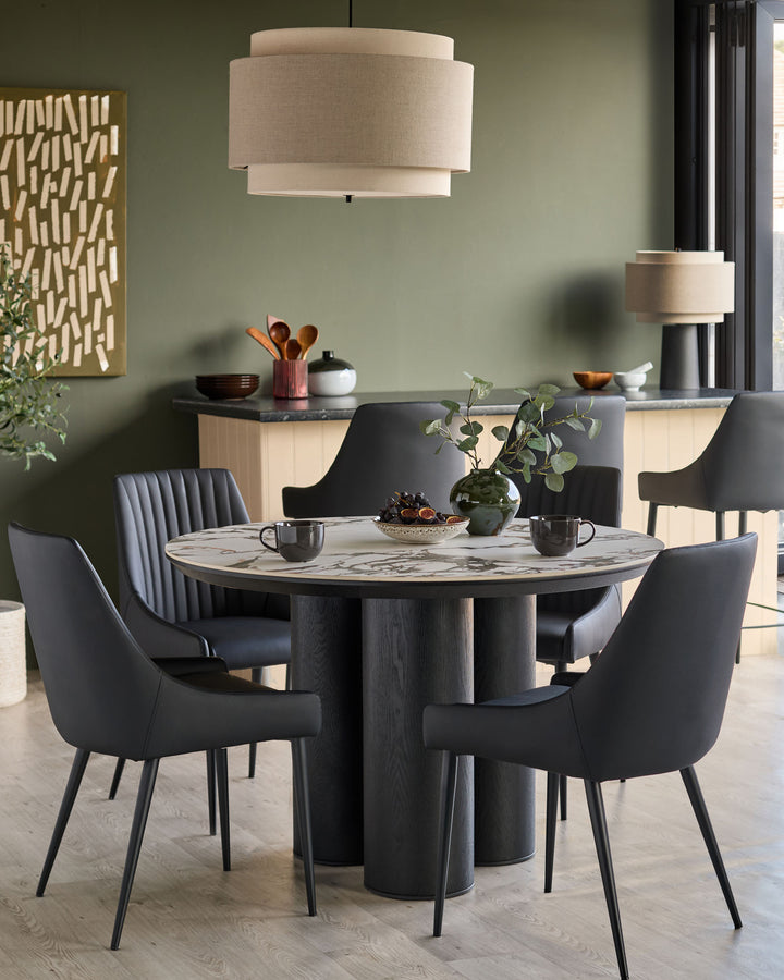 Blakely black faux-leather dining chair with curved back and tapered metal legs, shown in modern dining setting.