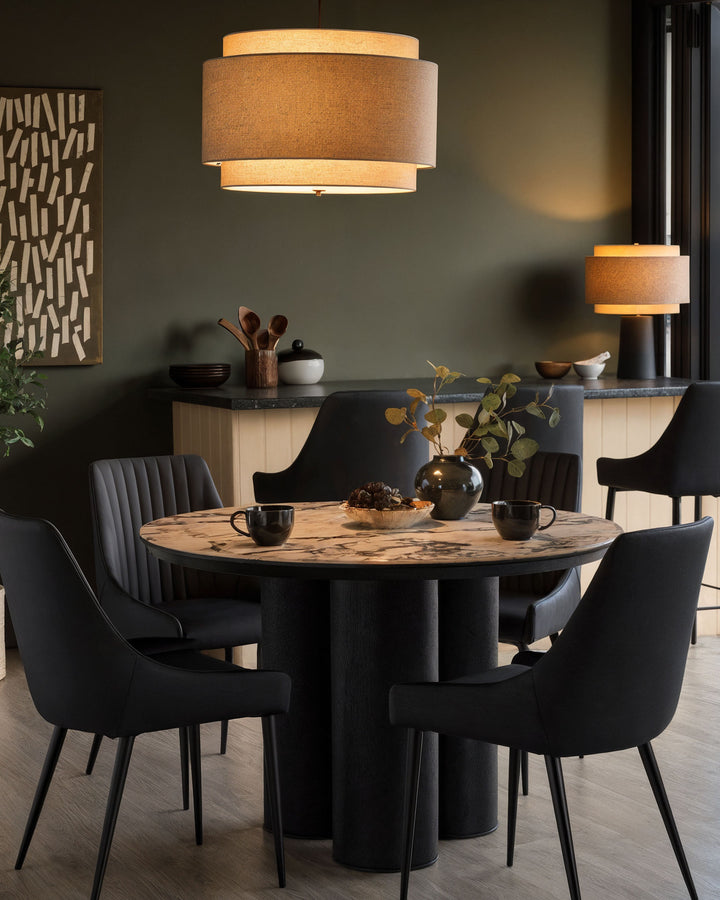Blakely faux leather dining chair in black, shown in a modern dining room setting around a round table.