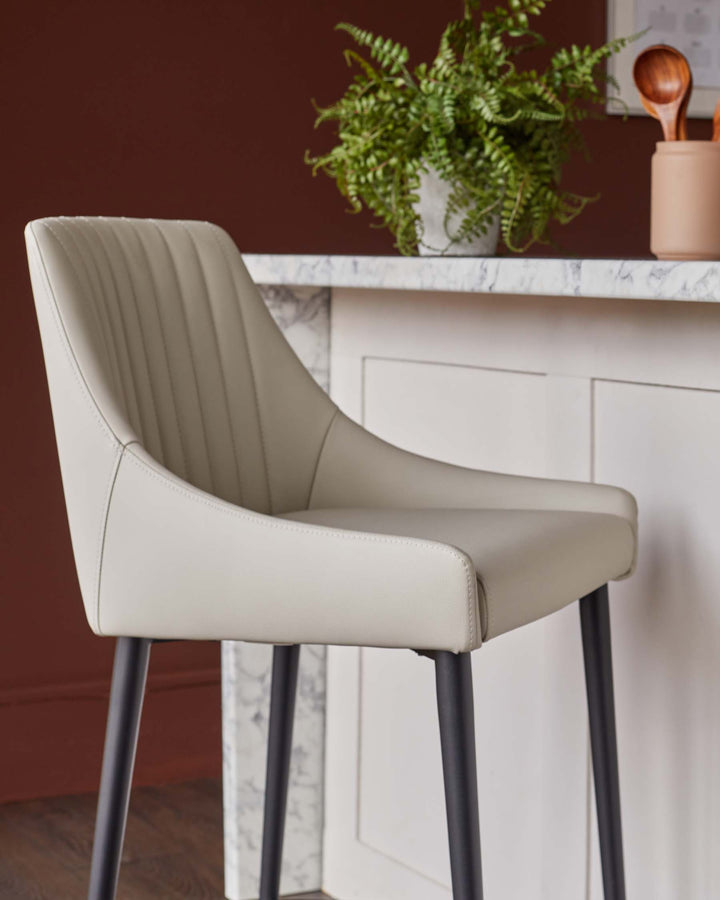 Close up of a stylish kitchen stool with beige cushioning and sleek black legs, perfect for any modern kitchen space.
