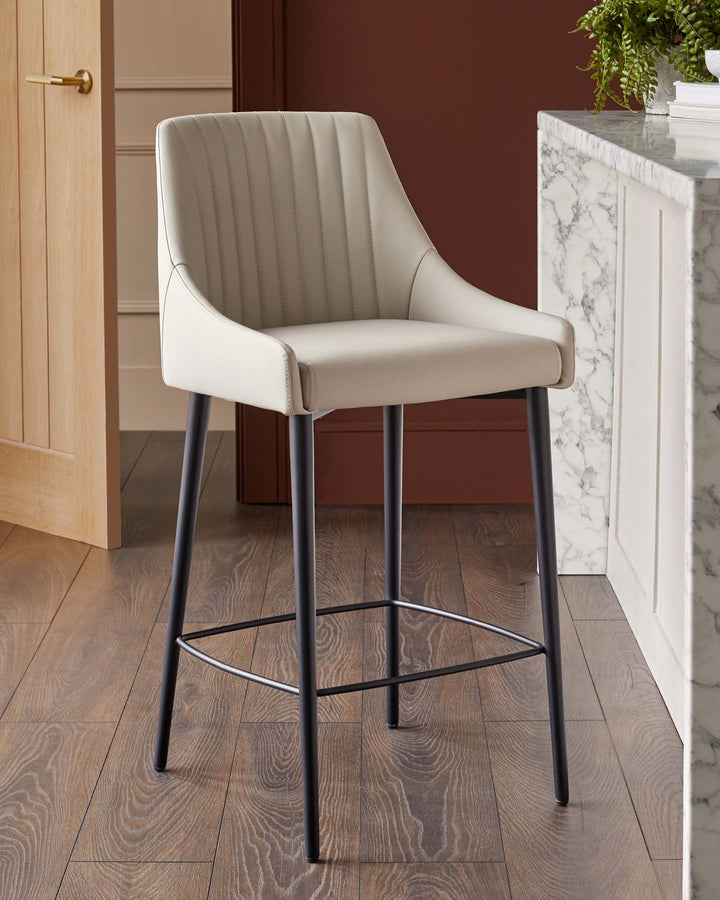 A modern, cream-coloured bar stool with black legs, sitting on a wooden floor in front of a white marble counter top.
