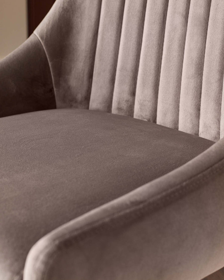 Close-up of a stylish, taupe-coloured armchair with vertical channel tufting. Comfortable and elegant seating.