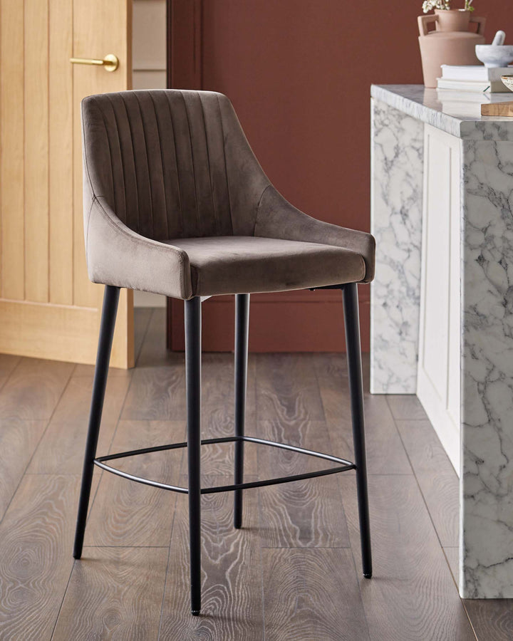 A stylish bar stool with a soft, brown upholstered seat and sleek black legs, perfect for modern kitchens and bars.