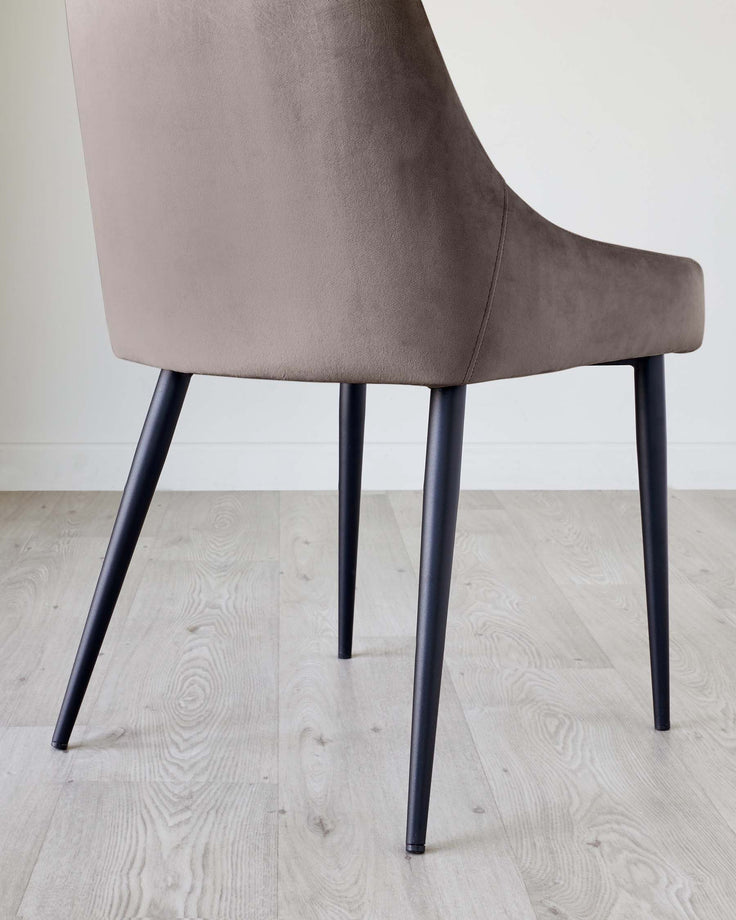 A modern chair with mocha upholstery and black legs. A stylish piece for any dining or living space.