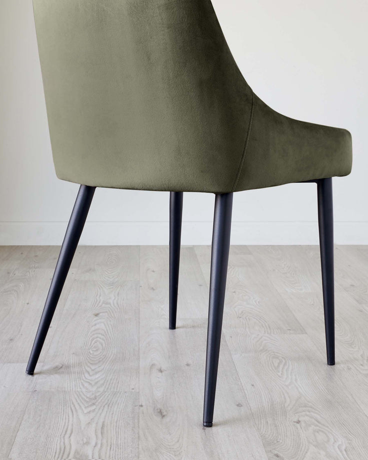 Blakely velvet dining chair in olive green, shown from back angle with dark tapered legs on light wood flooring.