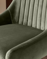 Blakely bar stool in olive green velvet, showing pleated backrest and curved seat from side angle.