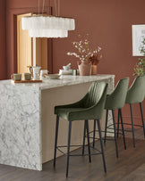 Blakely bar stool in olive green velvet with black metal legs, shown in kitchen island setting.