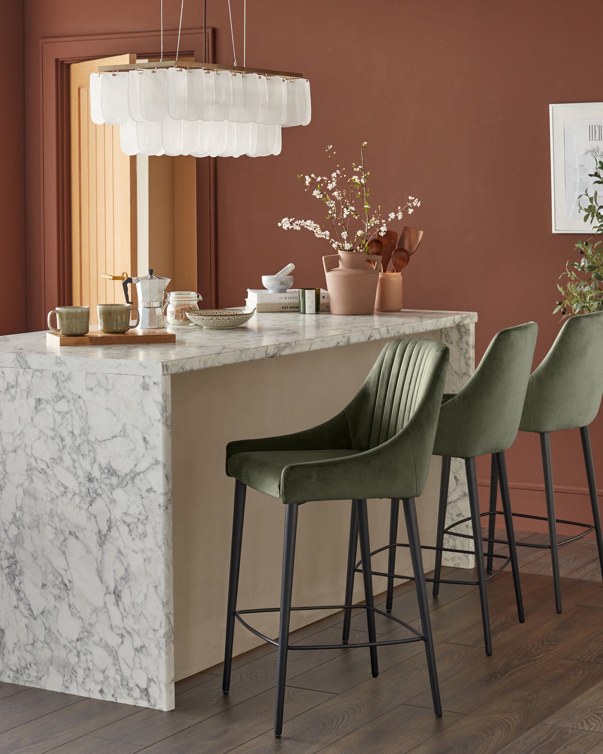 Blakely bar stool in olive green velvet with black metal legs, shown in kitchen island setting.
