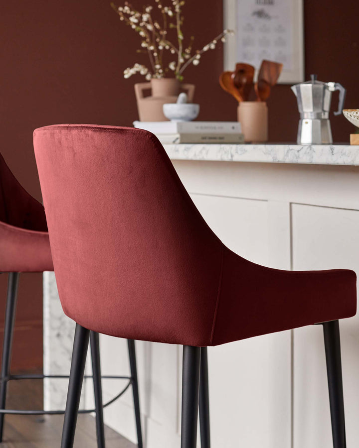Close-up of a stylish, red velvet bar stool with black legs, set against a kitchen counter backdrop.