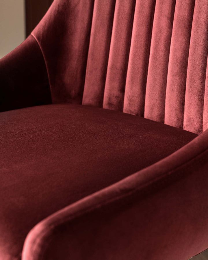 Burgundy velvet chair with vertical channel tufting on the back. Close-up shows the plush seat and armrests.