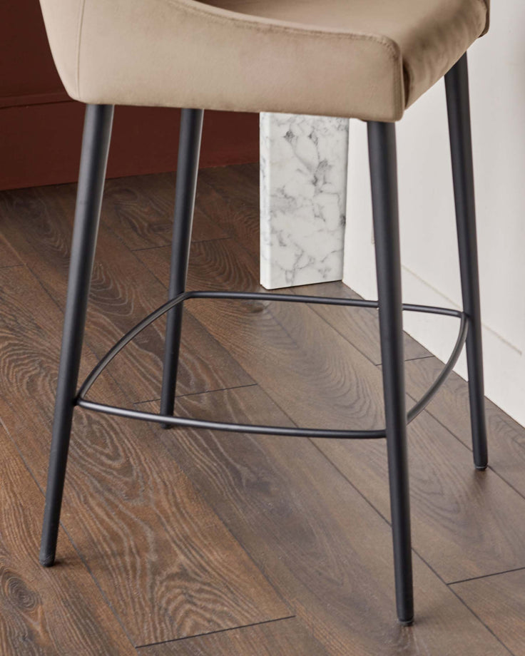 Close-up of a modern stool with a padded seat and black metal legs, showcasing its minimalist design.