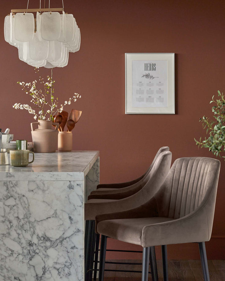 Stylish kitchen with marble countertop, bar stools, decorative vases, and a modern chandelier.