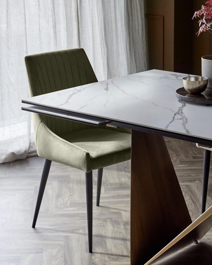 Blakely velvet dining chair in olive green, shown at a marble table with black legs and wood base.