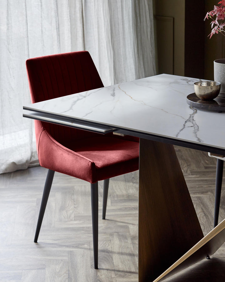 A stylish dining room featuring a red velvet chair and a modern marble-effect dining table with a dark frame.