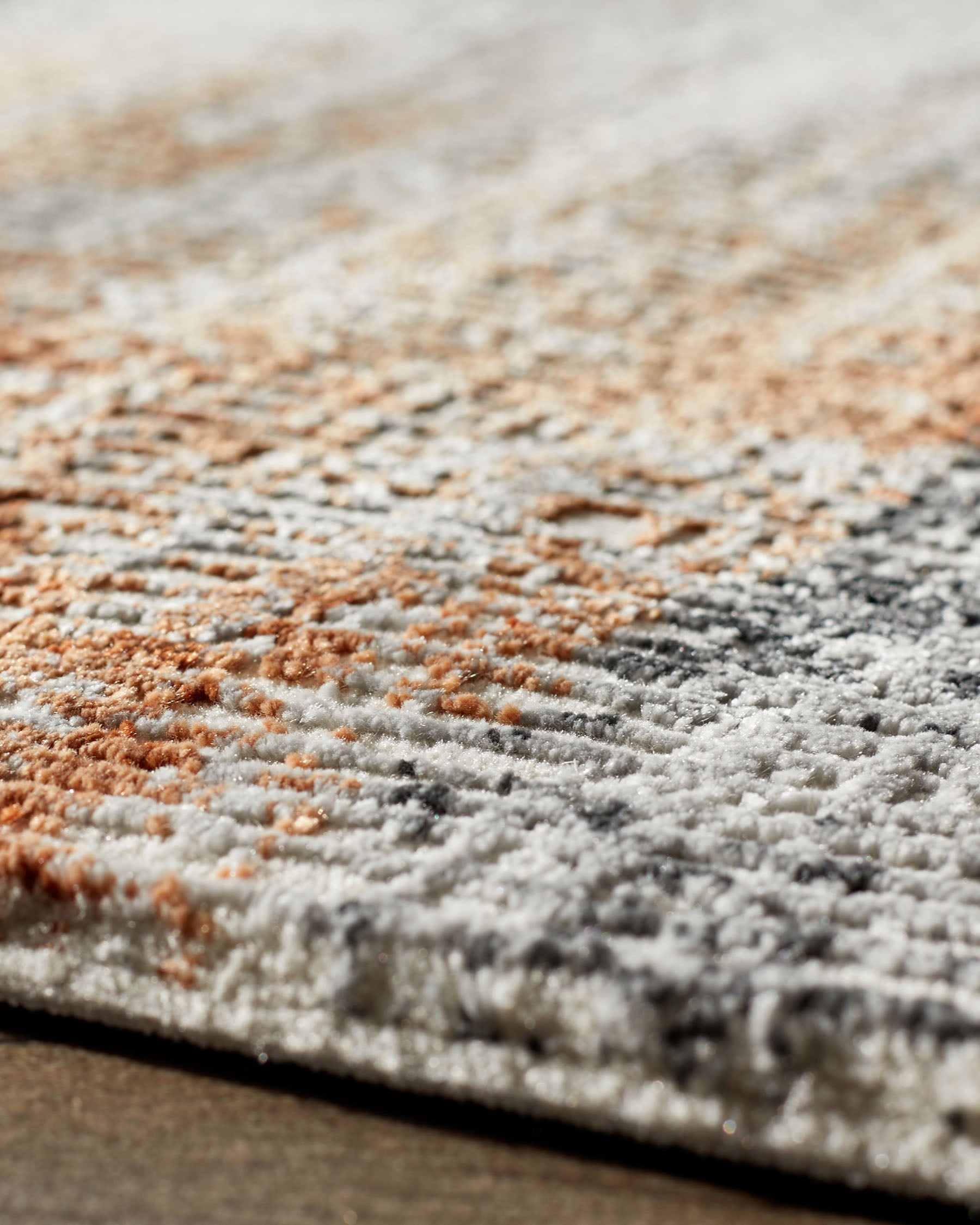 Close-up of a soft-touch textured rug in terracotta and cream tones showing detailed pile texture.