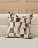 Bridget cushion in chocolate and cream with geometric patterned design, displayed on a neutral sofa.