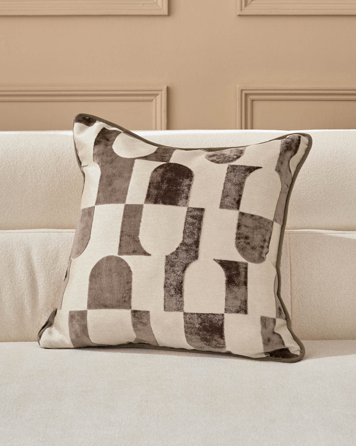 Bridget cushion in chocolate and cream with geometric patterned design, displayed on a neutral sofa.
