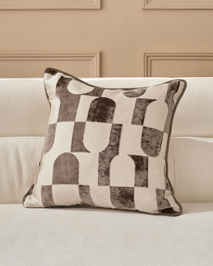 Bridget cushion in chocolate and cream with geometric patterned design, displayed on a neutral sofa.
