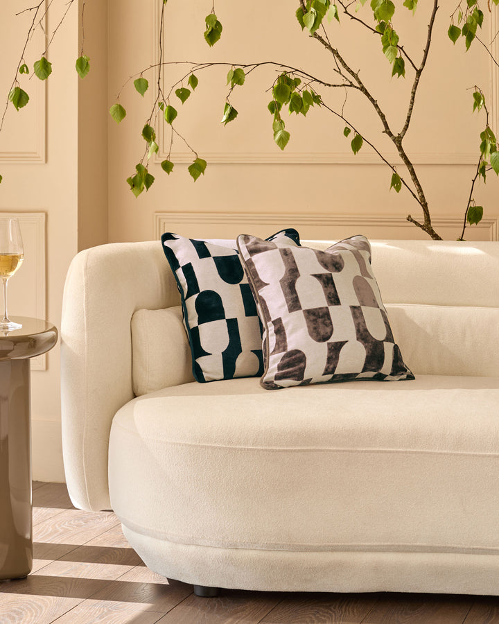 Bridget Medium Cushion in black and cream geometric pattern, displayed on a cream upholstered armchair.