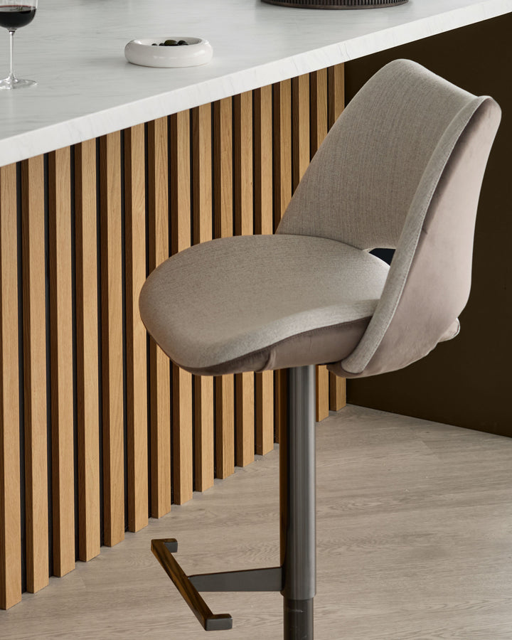 Bronwyn gas lift bar stool in natural fabric with mocha base, shown at counter height against vertical wood paneling.