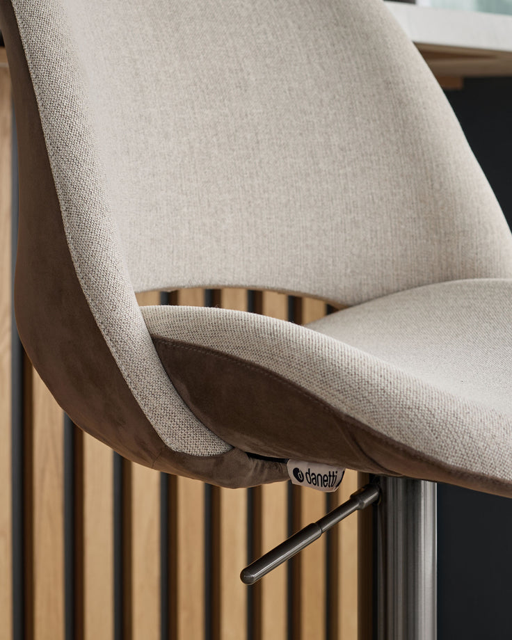 Bronwyn gas lift bar stool in natural fabric and mocha velvet, side angle view showing curved backrest and metal base.