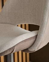 Bronwyn gas lift bar stool in natural fabric with mocha base, close-up detail of curved armrest and seat.