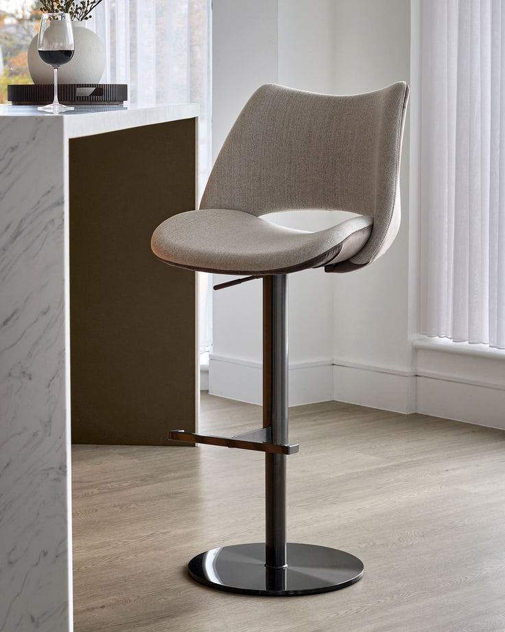 Bronwyn gas-lift bar stool in natural fabric with mocha velvet seat, black metal base, shown in modern kitchen setting.