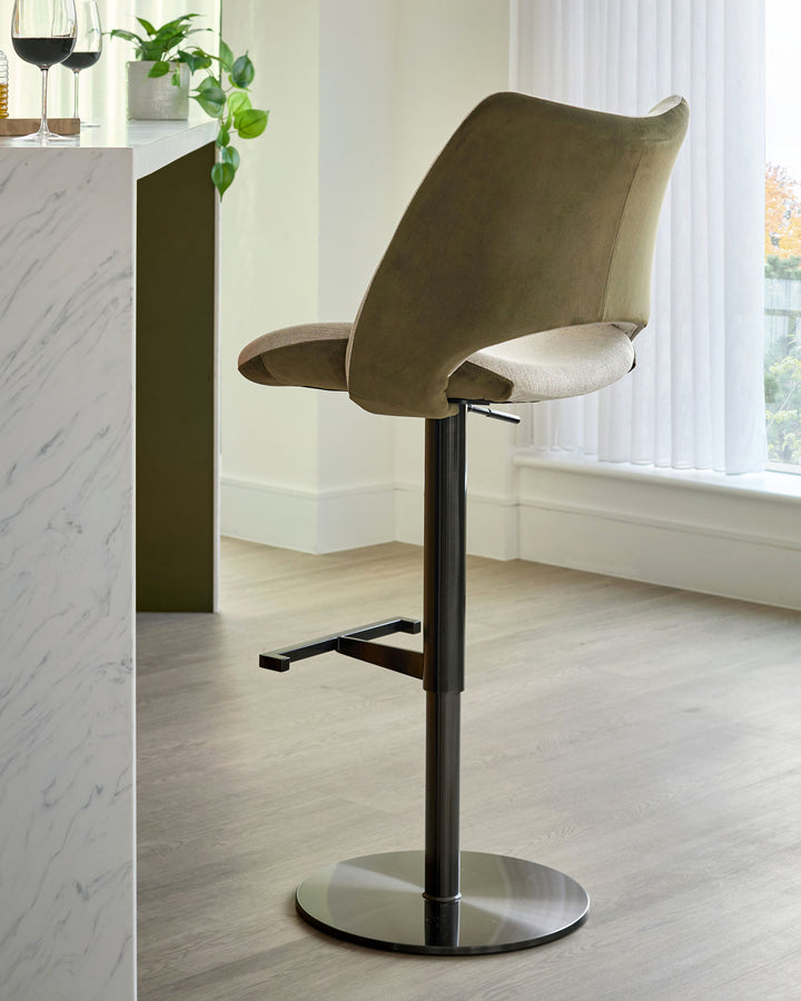 Bronwyn gas lift bar stool in olive green velvet and natural fabric, featuring a black pedestal base and footrest.