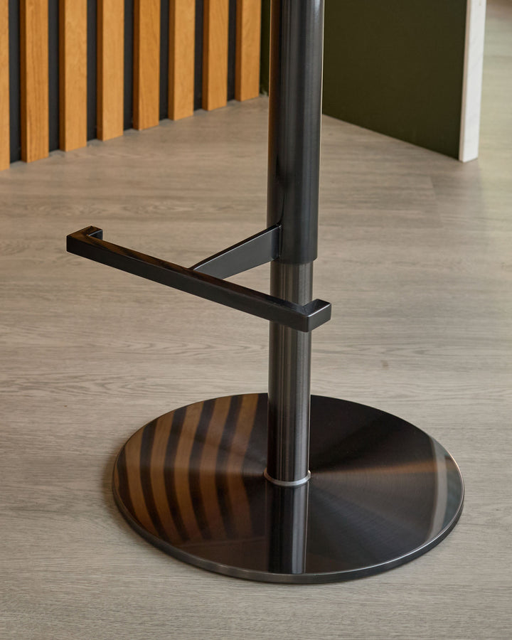 Black gas-lift bar stool with metal base and wooden armrest, shown in modern interior setting.