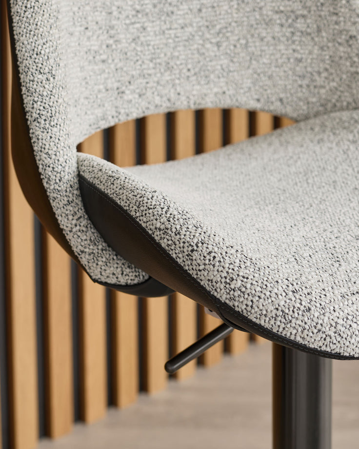Bronwyn gas-lift bar stool with grey fabric seat, black metal base, and wooden slat backrest detail.