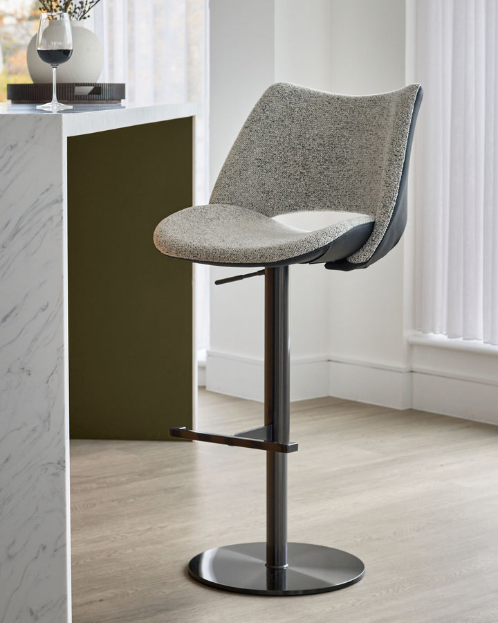 Bronwyn grey fabric and black faux leather gas lift bar stool with black metal base, shown in modern kitchen setting.